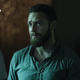 Aaron, in a teal, polka-dotted shirt, looks skeptically at an unknown figure.